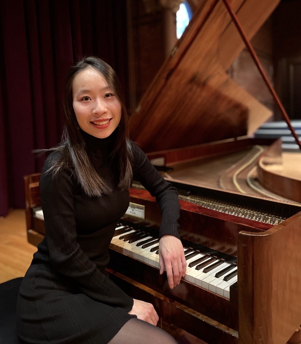 A woman sitting by a grand piano